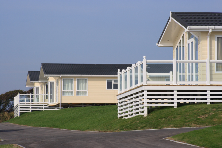 Three holiday homes perched on a grass bank with verandas renting an apartment