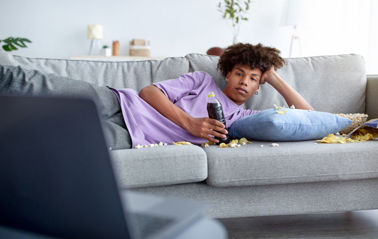 Bored teen guy lying on sofa mobile home