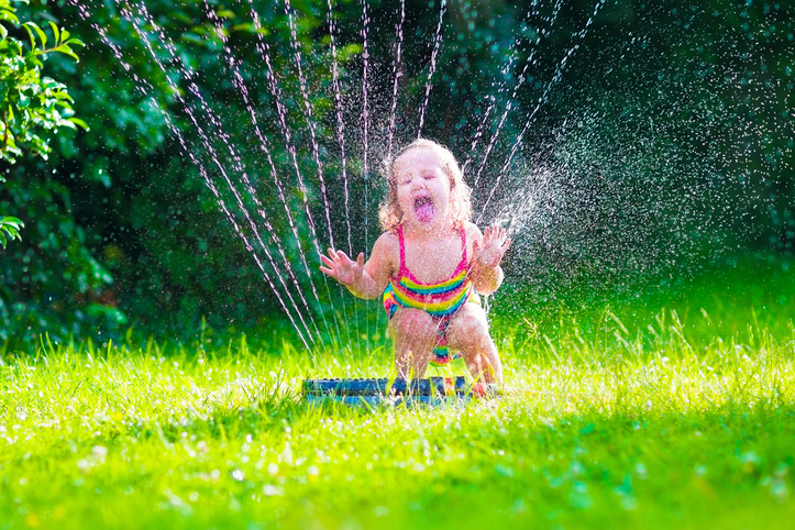 Child playing with garden sprinkler