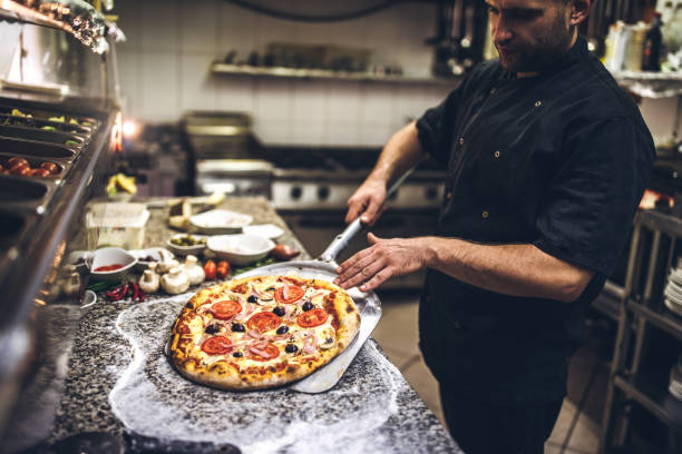 Young Chef Preparing Pizza In Kitchen Restaurant